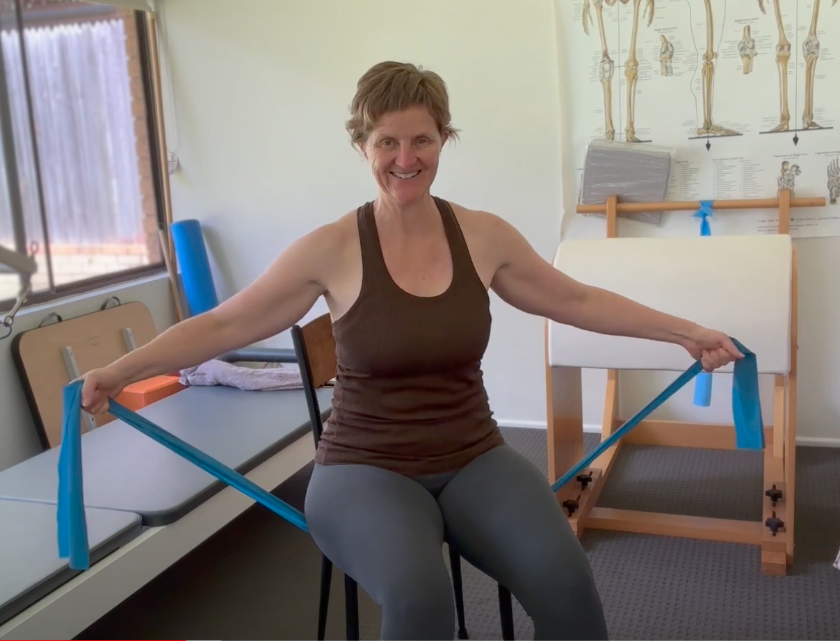 A woman doing Chair Pilates, smiling